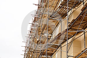 Metal scaffolding with wooden decking built around a historic building for restoration work and renovation of the facade. Construc