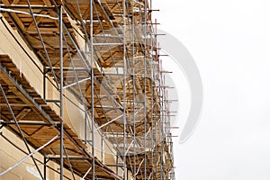 Metal scaffolding with wooden decking built around a historic building for restoration work and renovation of the facade. Construc