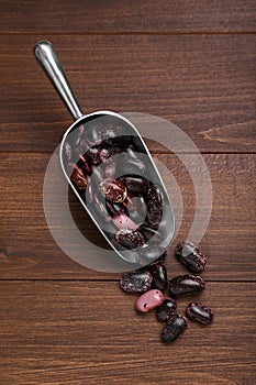 Metal scoop with dry kidney beans on wooden table, flat lay