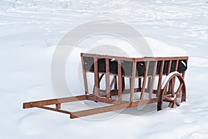 Metal sculpture of a carriage covered with snow and stands in the middle of a snowy field, winter background