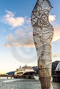 Metal sculpture on dock with cruise ships, late afternoon. Juneau, Alaska, USA.