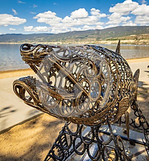Metal sculpture of fish on a beach of Penticton BC Canada. Art object in the shape of an salmon fish