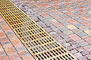 metal sewer grate for drainage system on wet cobblestone sidewalk