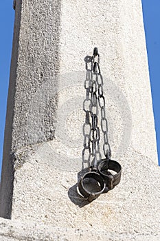 Metal shackles hang from a concrete pillar of shame, chaining people in old Europe Austria, Retz,