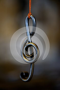 A metal sheet music key hangs in a rope in a blacksmith`s workshop