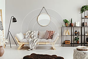beige wall in stylish boho living room with elegant sofa and fury carpet photo