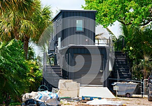 Metal shipping container house under construction on piece of land with lush green trees