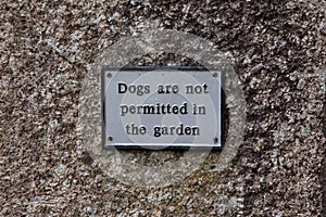 A metal sign advising `dogs are not permitted in the garden`