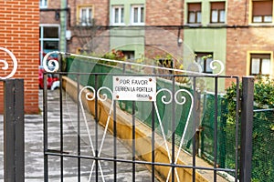 A metal sign on the gate with an ornate iron pattern at the entrance courtyard