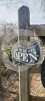 Metal sign on outside wooden post stating we are open. photo