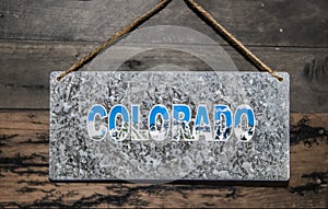 Metal sign saying Colorado with mountains inside letters haning on rough rustic wooden wall photo