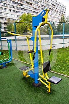 A metal simulator of bright yellow and blue color on a sports field with a rubberized coating against a background of greenery