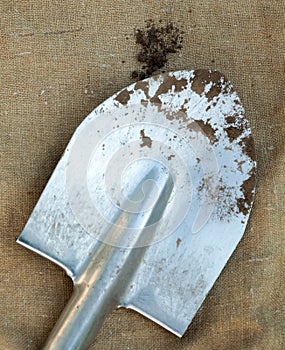 Metal spade and black soil on the sackcloth