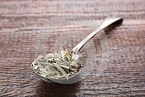 Metal spoon with aromatic dried lemongrass on wooden table