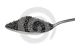 Metal spoon with roasted black sesame seed close up on white background