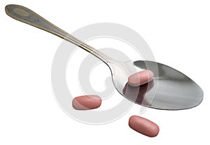 Metal spoon and tablets on a white background