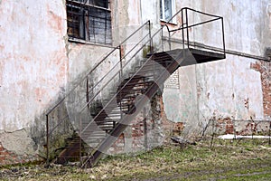 Metal staircase along the wall of an old building. Abandoned building. Production room