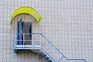 Metal staircase and an open door on a brick wall of house