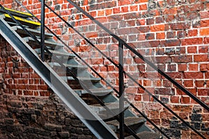 Metal stairway against old brick wall