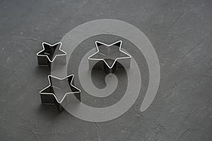 Metal stars on black festive background. Baking molds. Cookie cutters. Flat lay, top view