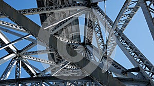 Metal steel girders on a bridge from below against blue sky