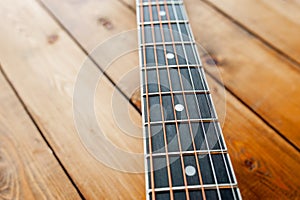 Metal strings on the neck of an acoustic guitar on wooden boards, close-up