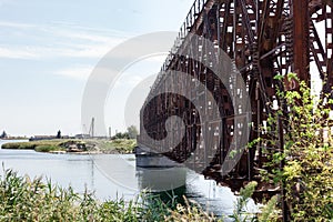 The metal structure of the old bridge across the strait . Old railway, road and pedestrian bridge