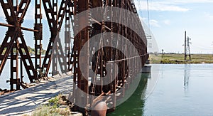The metal structure of the old bridge across the strait . Old railway, road and pedestrian bridge. Henichesk Strait