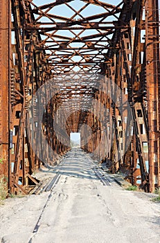 The metal structure of the old bridge across the strait . Old railway, road and pedestrian bridge. Henichesk Strait