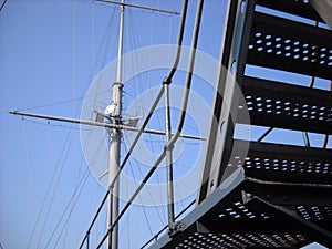 Metal structures on the deck of a warship. Aerial or mast mast with a round antenna. Steel cables and stairs. Water transport