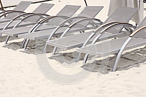 Metal sun lounger chairs on sand