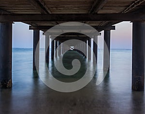 Metal supports of the pier at dawn. View of the pillars under th