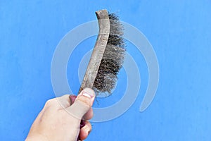 Metal surface cleaning brush in hand on a blue background