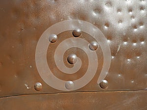Metal surface with rivets and bolts. Abstract background of a military or industrial nature. Sheathing with dents, seams and nuts