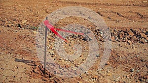 Metal survey peg with red flag on construction site