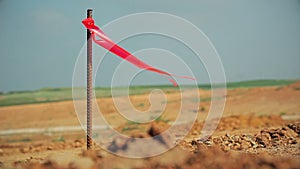 Metal survey peg with red flag on construction site