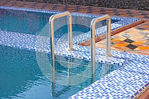A metal swimming pool safe ladder (skimmer) on the entrance to the home inground poolside