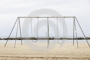 Metal swings on a sandy beach near the ocean