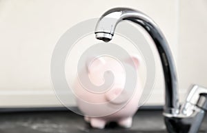 Metal tap and blurred piggy bank. Water saving concept