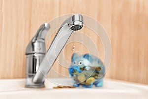 Metal tap and piggy bank on sink. Water saving concept