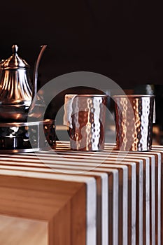 A metal tea set on an unvarnished wooden table