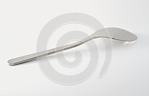 Metal teaspoon on white specular surface