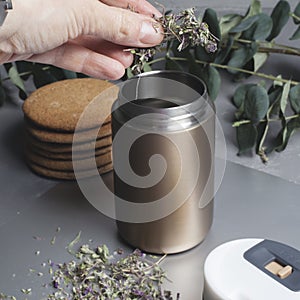 Metal thermos mug for brewing herbal tea. Hand pour dry herbal tea into a mug