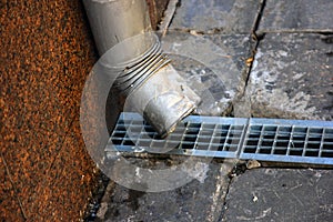 metal tinplate downpipe and drain tray with grating closeup