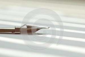 Metal tip for the ink pen on a white background in solar rays. stationery on white desk close up side view. spelling lessons and
