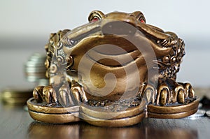 A metal toad next to a stack of coins.