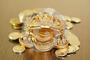 A metal toad next to a stack of coins.