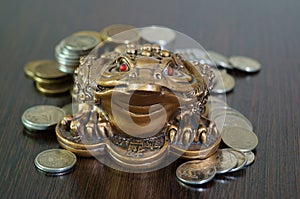 A metal toad next to a stack of coins.