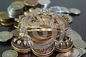 A metal toad next to a stack of coins.