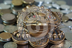 A metal toad next to a stack of coins.